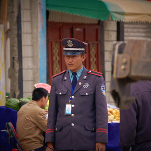 སྲིད་གཞིའི་སྲོང་བཙན་གནས་ལྕགས་ལོའི་གོ་འཛུགས་དང་མི་ལྕགས་ (mkha' 'gro'i gong phel) Guardian of Order: Tibetan Policeman in Lhasa Marketplace Giclee / Colored / 8 x 10 Tracy McCrackin Photography Wall art - Tracy McCrackin Photography